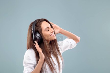 Portrait d'une fille heureuse écoutant de la musique avec des écouteurs sans fil à partir d'un smartphone. Fille utilise des écouteurs sans fil et la danse
.