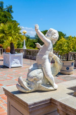 Foto de Castillo de Hearst, California, EE.UU. - 27 de abril de 2017- Pequeña estatua de mármol de Cupido en el patio de Casa Del Mar con vistas al Océano Pacífico. Casa Del Mar es una de las tres mansiones de huéspedes en la propiedad del castillo de Hearst. - Imagen libre de derechos