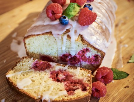 Warm baked plumcake or plum cake with seasonal raspberries. Enticing raspberry bundt cake or fruitcake with veil of sweet sugarcoat. Exquisite slice of plumcake or genoa cake with fresh raspberry