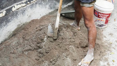 Foto de Trabajador asiático usando azada para mezclar la potencia del cemento con arena - Imagen libre de derechos