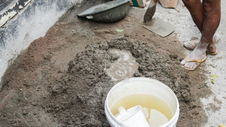 Foto de Trabajador asiático usando azada para mezclar la potencia del cemento con arena - Imagen libre de derechos