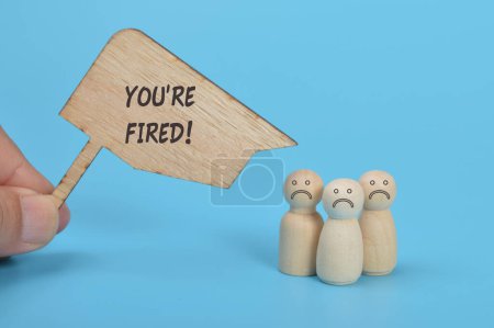 Photo for Sad wooden figure of people with text YOU'RE FIRED! - Royalty Free Image