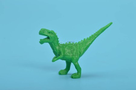Téléchargez les photos : Jouet dinosaure T-Rex vert isolé sur un fond bleu - en image libre de droit