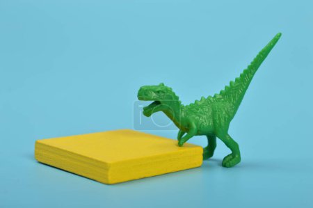 Téléchargez les photos : Jouet dinosaure T-Rex vert isolé sur un fond bleu. - en image libre de droit