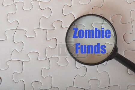 Photo for Magnifying glass with text ZOMBIE FUNDS.A zombie fund (more formally known as a closed fund) is a colloquial expression for a with-profits life insurance fund that is closed to new business. - Royalty Free Image