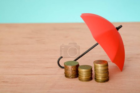 Photo for Red umbrella and coins with copy space. Money protection and safety assurance concept - Royalty Free Image