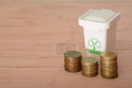 Foto de Monedas de oro y una papelera de reciclaje, el concepto de costo de reciclaje para la sostenibilidad verde, y la preservación del medio ambiente. - Imagen libre de derechos