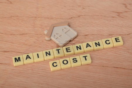 Spielzeughaus-Modell mit Text MAINTENANCE COST.Housing cost concept