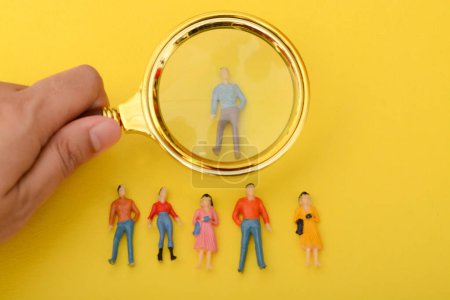 The group of staff, armed with a magnifying glass, scoured the job applications, searching for the ideal candidate to hire.