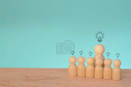 Photo pour Les figures en bois réfléchissaient autour d'une ampoule lumineuse, symbolisant la naissance d'idées novatrices et le pouvoir de la prospective dans le domaine de la créativité. - image libre de droit