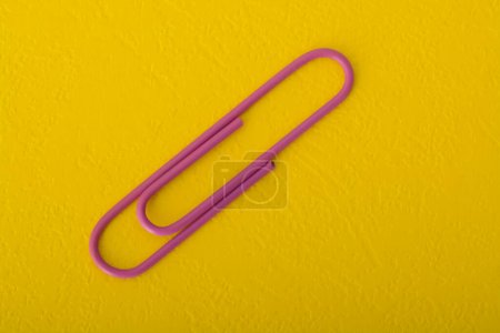 Foto de Clip de papel púrpura aislado sobre un fondo amarillo. - Imagen libre de derechos