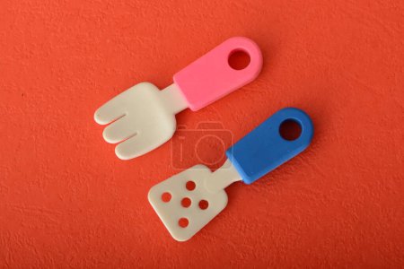 Photo for Toy rubber scraper and fork isolated on a red background. - Royalty Free Image