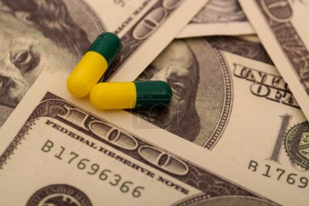 La juxtaposition de piles de pièces de monnaie à côté des pilules et capsules médicales souligne la réalité de la médecine coûteuse
