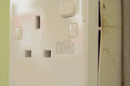 A damaged electrical domestic power socket with visible cracks poses a serious risk of electrocution or fire