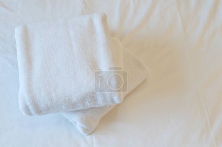 Las toallas blancas colocadas en la cama indican la importancia de la higiene y la limpieza en la habitación del hotel.