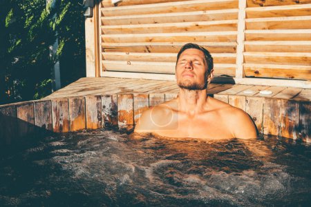 Foto de Hombre relajante en bañera de hidromasaje de madera al aire libre. .. Foto de alta calidad - Imagen libre de derechos