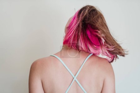 Back view trendy cheerful young woman with gemini dyed hair shaking her head. 