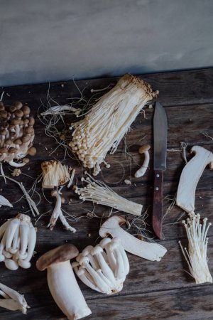 Foto de Various edible Asian mushrooms. Enoki, shimeji, shiitake, tea tree, royal oyster mushrooms. Set of vegetables. Dark photo natural light. Flatly. - Imagen libre de derechos