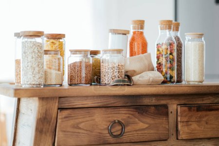 Foto de Zero waste concept. Textile eco-bags, glass jars with grocery on a wooden table in the kitchen. Eco-friendly reuse concept. Selective focus. - Imagen libre de derechos
