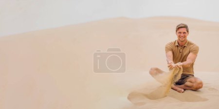 Foto de Hombre guapo con elegantes trajes de colores tierra disfrutando de la arena en las dunas del desierto. Banner. - Imagen libre de derechos