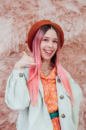 Photo for Give me call. Stylish millennial teenager girl with color hair showing phone sign near face. Portrait of a romantic young woman in a beret on a pink background. - Royalty Free Image