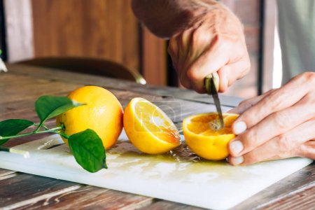 Téléchargez les photos : Mains masculines coupant des fruits orange mûrs juteux et le partageant avec son fils. Aliments sains - en image libre de droit