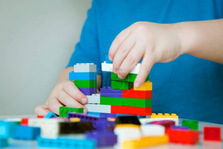 Foto de Boy plays colorful multi-colored cubes and cars on the table. Early development and learning. . High quality photo - Imagen libre de derechos