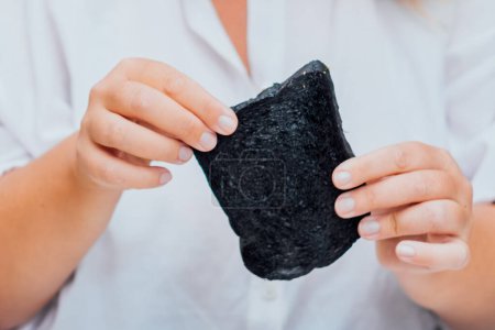 La mujer saborea el sabor único del pan infundido en carbón, capturando un momento de curiosidad culinaria y una alimentación aventurera.