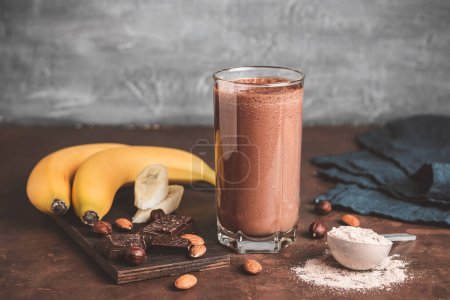 Photo for Chocolate milkshake smoothie with banana, protein powder and nuts on dark background. - Royalty Free Image