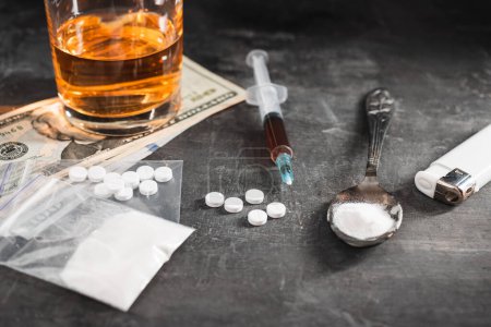 Photo for Alcohol drink in a glass, syringe with a dose of drugs, white pills in a transparent bag, narcotics powder in a spoon and US dollar cash on dark background. Concept of addiction and bad habits. - Royalty Free Image