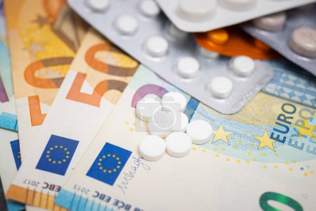 Photo for White round pills, blister packs with tablets, antibiotic, painkiller or drugs and money, Euro currency banknotes, expensive medicine and healthcare concept, close-up view. - Royalty Free Image