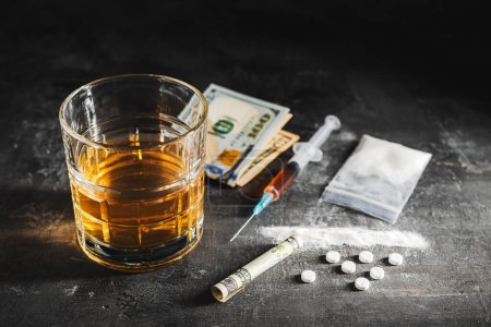 Photo for Alcohol drink in a glass, syringe with a dose of drugs, white pills, narcotics powder in a transparent bag and US dollar currency cash on a dark background. Concept of addiction, abuse and bad habits. - Royalty Free Image