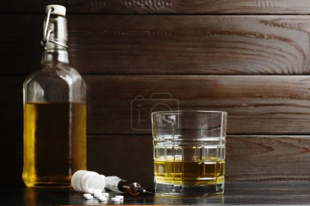 Photo for Alcohol drink in a glass, white pills, syringe with drug substance, heroin dose on wooden table. Concept of addiction and bad habits. - Royalty Free Image