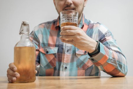 Téléchargez les photos : Homme accro et ivre à la table avec un verre de boisson alcoolisée, whisky ou brandy, alcoolisme et mauvaises habitudes concept. - en image libre de droit
