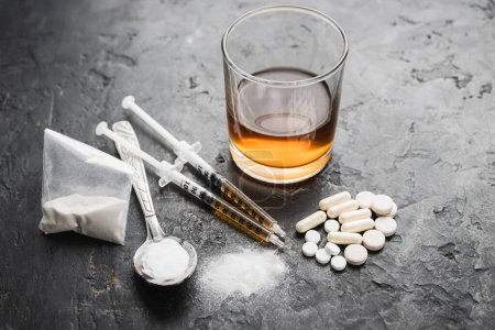 Photo for Narcotic substances in spoon, dope powder in transparent plastic bag, syringes with drugs dose, white pills and glass of alcohol drink on textured background. Concept of addiction and bad habits. - Royalty Free Image