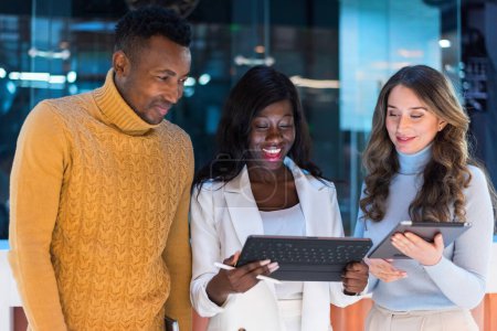 Téléchargez les photos : Multiracial group of people in an office discussing business using tablets - en image libre de droit