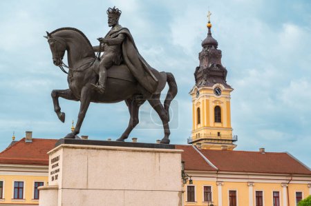 Foto de Vista de la estatua del rey Fernando I situada en la Plaza Unirii en el centro de Oradea, Rumania. Edificios de estilo clásico en el fondo - Imagen libre de derechos