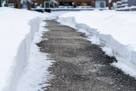 Primer plano del camino con sal para derretir la nieve en invierno cerca de las casas.