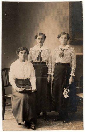 Foto de SOLINGEN, ALEMANIA - CIRCA 1920: Foto vintage muestra a tres mujeres posando para el fotógrafo. Foto en blanco y negro con tinte sepia. - Imagen libre de derechos