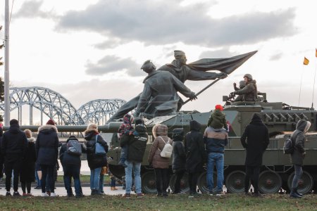 Téléchargez les photos : 18.11.2022 Riga, Lettonie. Défilé militaire les jours fériés. Les soldats conduisent dans des chars et saluent les gens du côté de la rue. - en image libre de droit