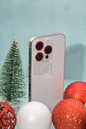 Foto de Riga / Letonia - 4 de diciembre de 2022: nuevo teléfono moderno - Iphone 14 pro entre las brillantes decoraciones navideñas sobre un fondo negro. Concepto de regalo de Navidad. Profundidad superficial del campo. - Imagen libre de derechos