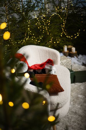 Téléchargez les photos : Intérieur de Noël avec un canapé blanc près des arbres de Noël verts avec des lumières qui créent un effet bokeh. deux pandas jouet doux avec un chapeau gnome rouge sur un canapé blanc. - en image libre de droit
