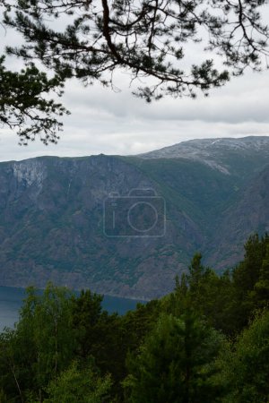 Naturblick auf die norwegischen Berge mit weißer Schneedecke auf der Höhe vom Stegastein-Aussichtspunkt an einem bewölkten Sommertag. Blaue UV-Strahlung in den Bergen.
