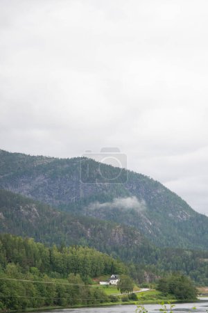 Schöne Landschaft mit Blick auf die norwegischen Berge mit grünen Nadelbäumen unter blauem Himmel am Flussufer.