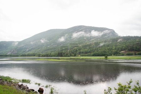 Schöne Landschaft mit norwegischen Bergen mit grünen Nadelbäumen an einem herbstlichen Regentag. Regentropfen fallen im Gebirgsfluss.