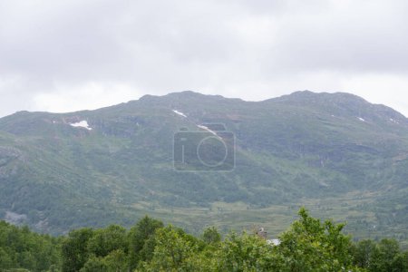 Landscape with a view of Norwegian mountains under a blue sky on a cloudy rainy summer day.