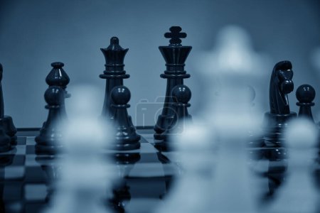 Téléchargez les photos : Pièces d'échecs noires fond blanc pièces d'échecs floues debout échiquier - en image libre de droit
