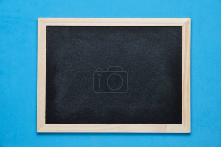 Black blackboard for notes in wooden frame blue background