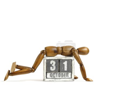 Photo for October 31, wooden calendar with mannequin lying on it on white background. Calendar date - Royalty Free Image
