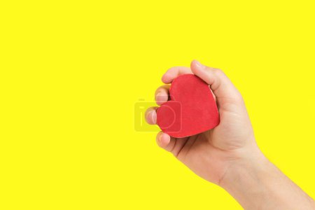 Photo for Heart in Hand Against Yellow Background. Evokes feelings of tenderness and sincerity, great for expressive visuals - Royalty Free Image